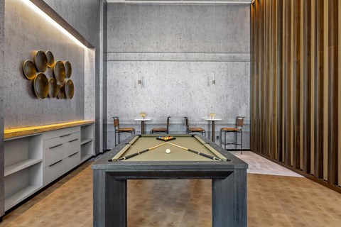 A pool table is in the middle of a room with a concrete wall and a striped wall.