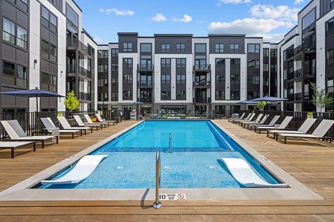 A large swimming pool in the middle of a resort area with lounge chairs on either side.