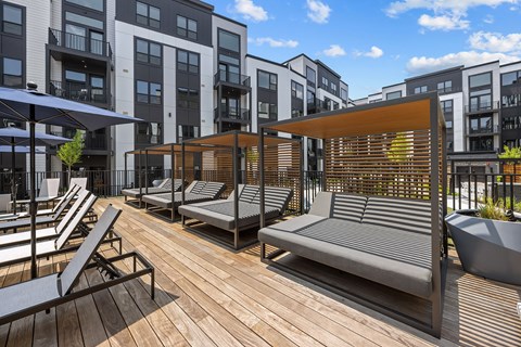A wooden deck with lounge chairs and umbrellas.