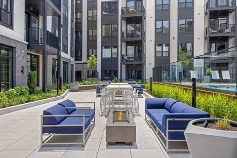 A modern outdoor seating area with blue cushioned benches and a fire pit.