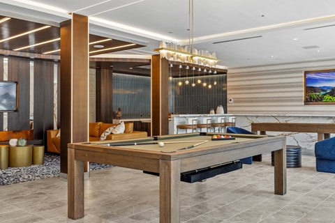 A billiard table is in the middle of a room with a TV on the wall.