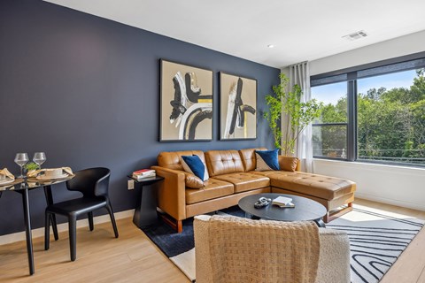 A living room with a brown couch and a painting on the wall.