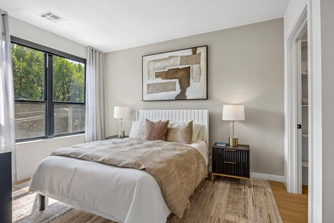 A bedroom with a large bed and a painting on the wall.