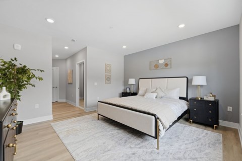 A bedroom with a large bed and a plant on the side table.