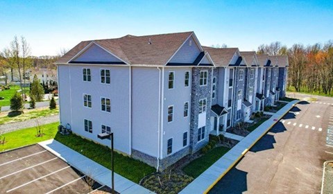 A row of white buildings with a parking lot in front.
