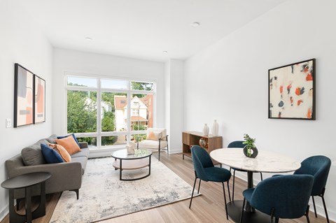 A living room with a grey couch, a white coffee table, and a round table with chairs.