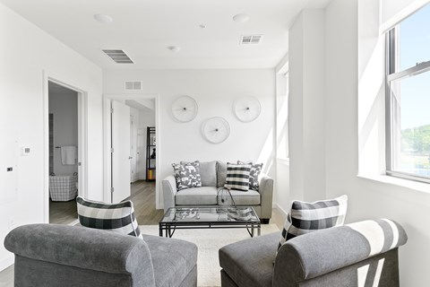 A living room with a grey couch and two grey armchairs.
