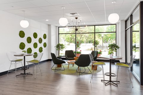 A room with a white table and chairs with a green wall decoration.