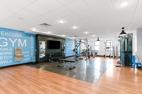 A gym with a variety of equipment and a wall with exercise motivation words.