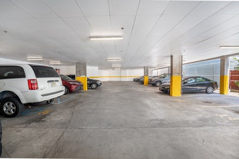 A parking garage with cars parked in yellow-painted spaces.