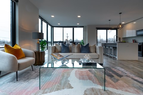 A modern living room with a glass coffee table and a grey sofa.