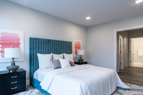 A bedroom with a large bed and a painting on the wall.