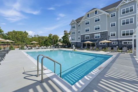 A large swimming pool in front of a multi-story residential building.