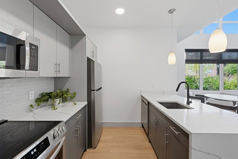 A modern kitchen with a stove, microwave, and refrigerator.