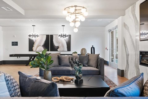 A modern living room with a grey couch and a chandelier.