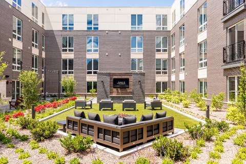 A courtyard with a fireplace and seating area surrounded by buildings.
