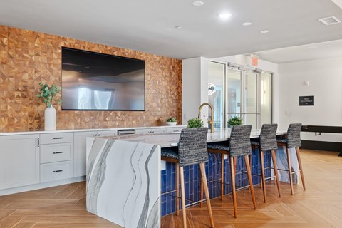 A modern kitchen with a bar area and a television mounted on the wall.