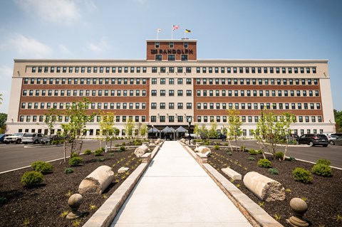 A large building with a flag on top and a walkway leading to the entrance.