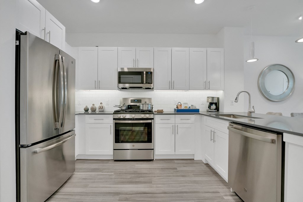 a large kitchen with stainless steel appliances and white cabinetry