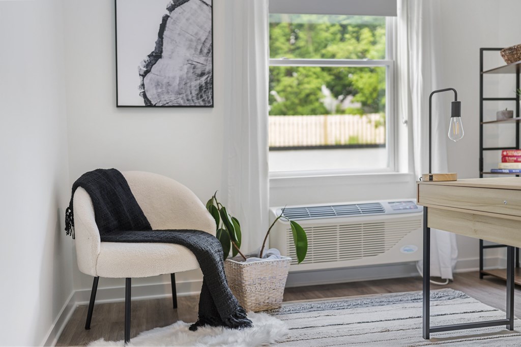 A chair with a black blanket draped over it sits in a room with a large window.