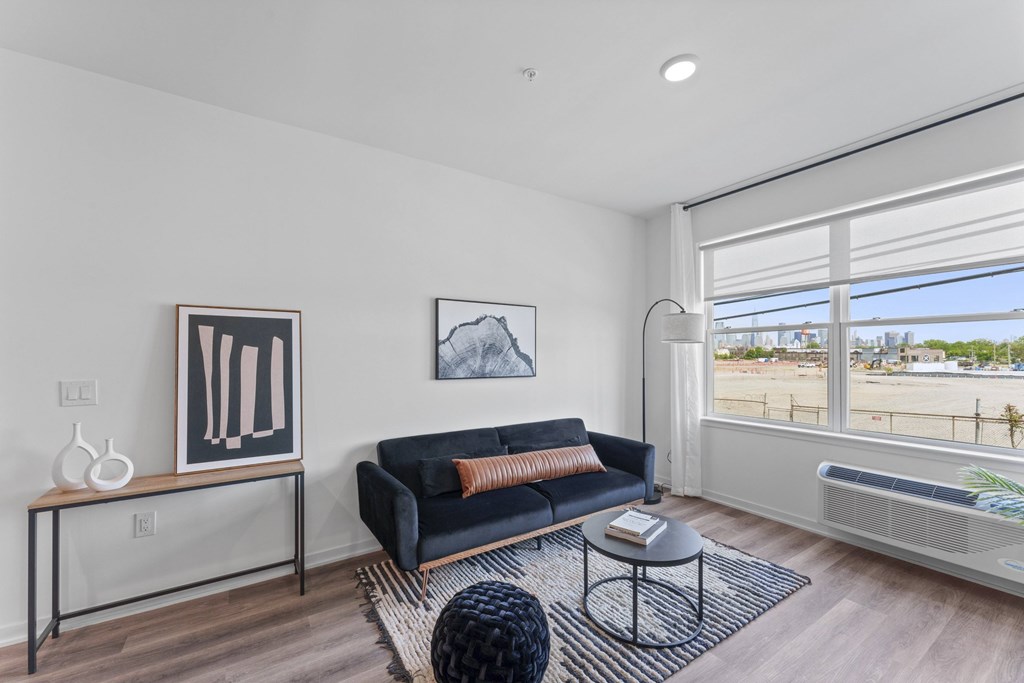 A living room with a black couch and a large window.