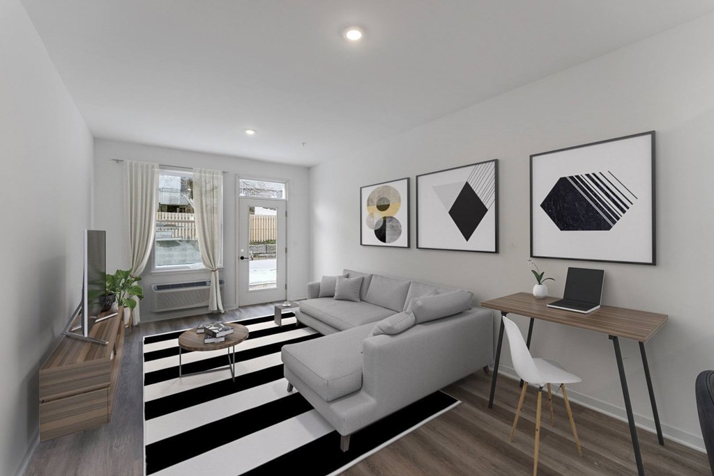 A modern living room with a grey sofa, a wooden table, and a black and white striped rug.