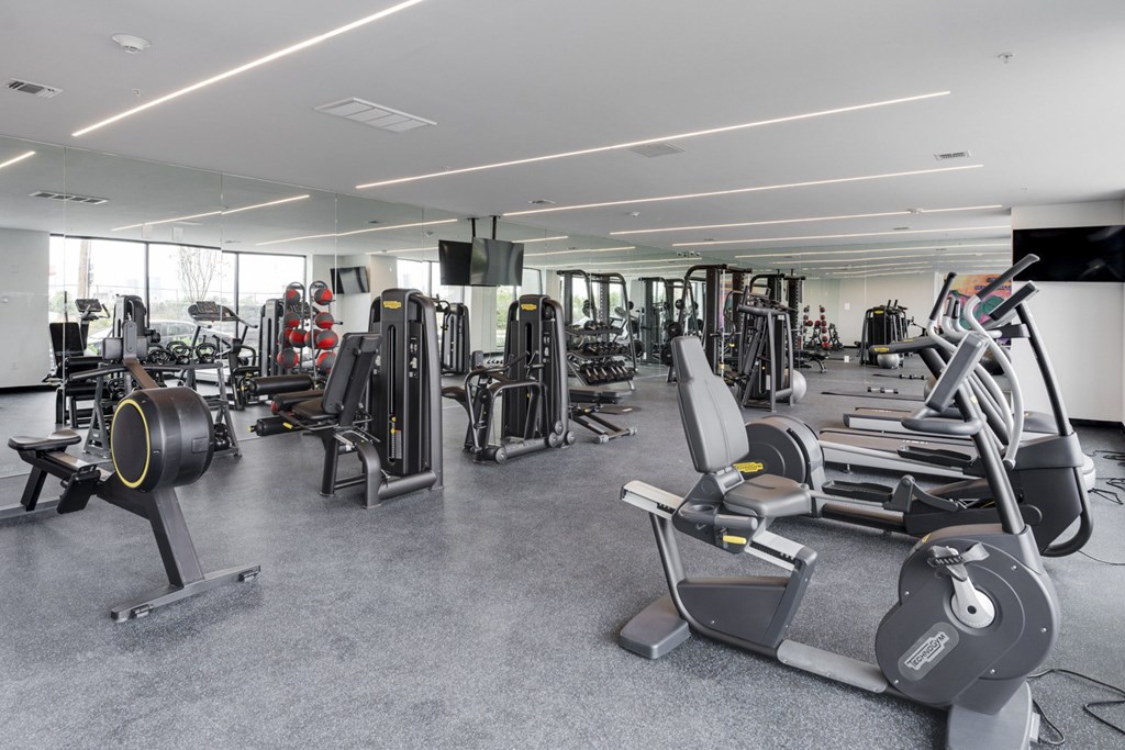 A gym with a variety of equipment including treadmills, weights, and exercise machines.
