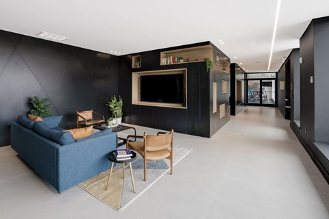 A living room with a blue sofa, a chair, a small table, and a television.