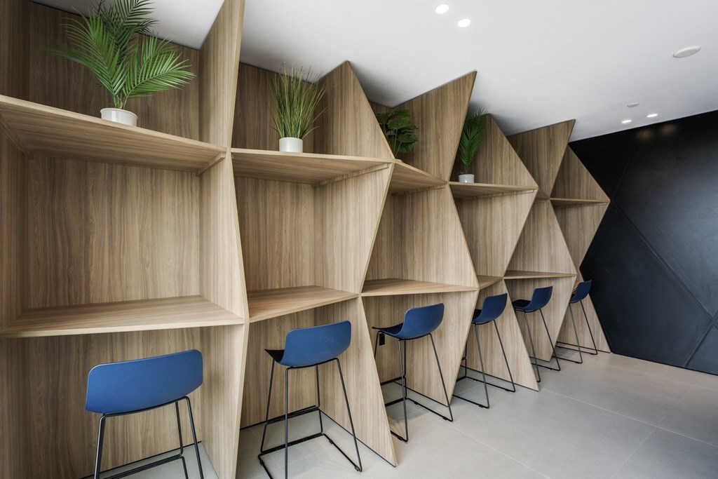 A row of blue chairs are in front of a row of shelves.