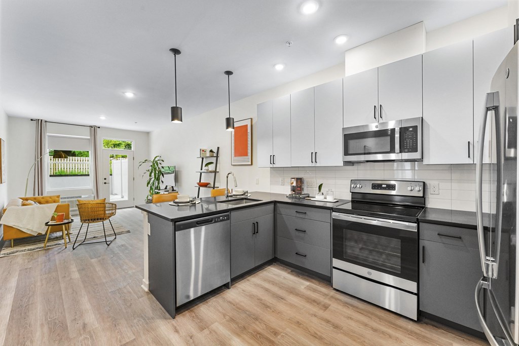 A modern kitchen with stainless steel appliances and wooden flooring.