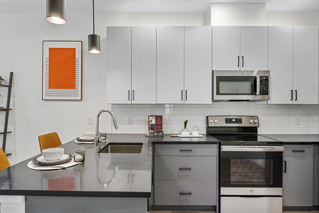 A modern kitchen with a black countertop and stainless steel appliances.