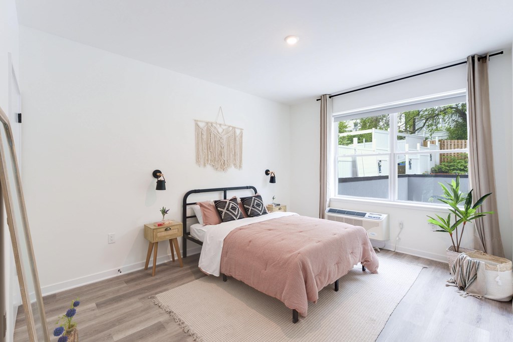 A bedroom with a bed, nightstand, and window.