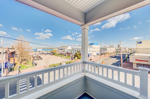 A balcony overlooks a street with buildings and a clear sky.