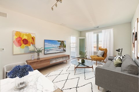 A living room with a grey couch, a coffee table, a painting, and a window with curtains.