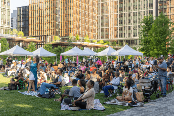A large group of people are sitting on the grass in a park.