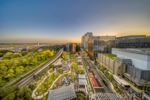 A city street with a red crosswalk and a large building in the background.
