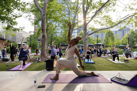 A woman in a white dress is doing yoga in a park.