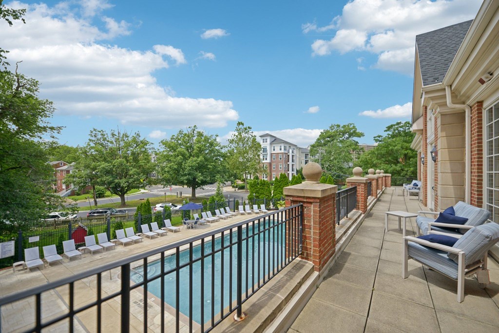 A pool surrounded by a fence and chairs.