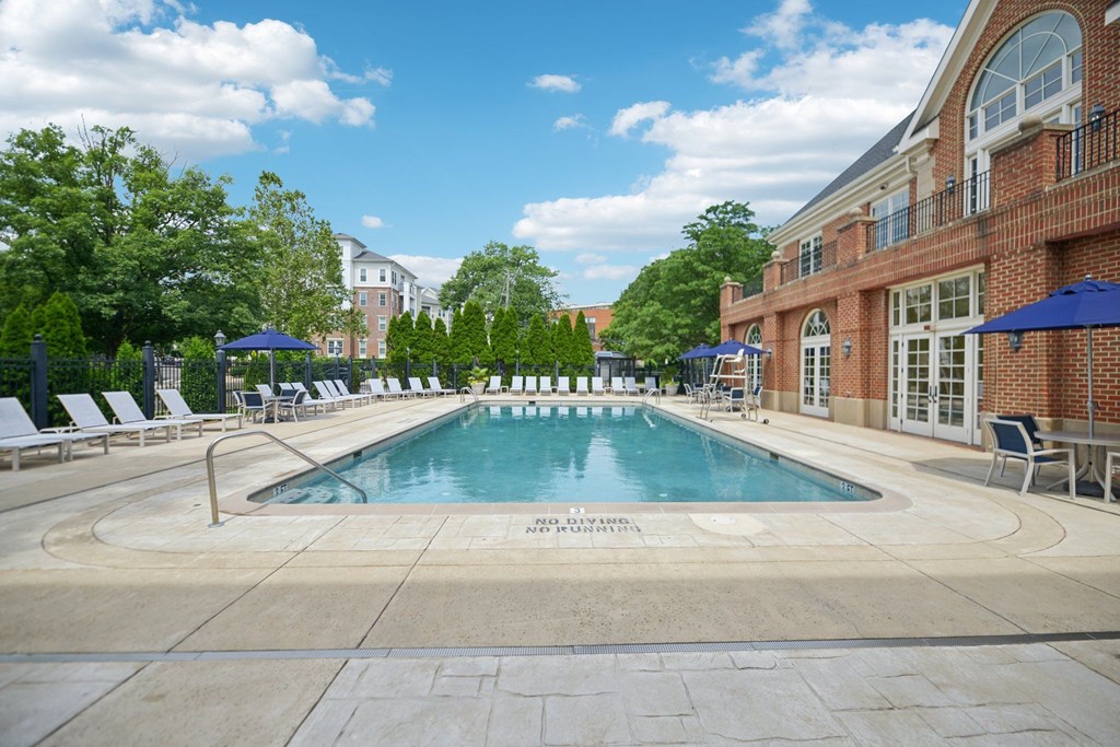 A large outdoor swimming pool surrounded by lounge chairs and umbrellas.