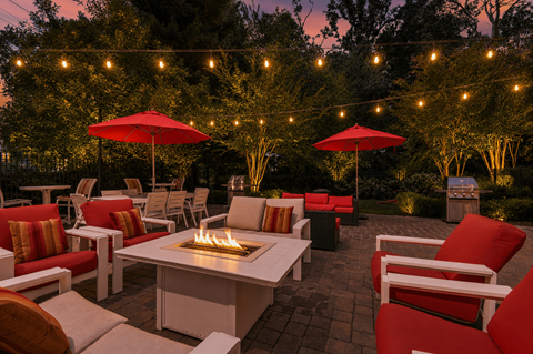 A patio with red chairs and a fire pit.