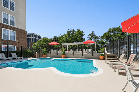 A pool with red umbrellas and chairs.