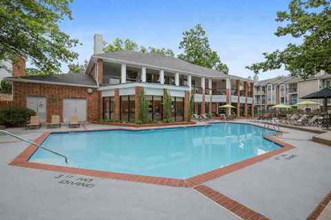 A pool surrounded by a brick building and trees.