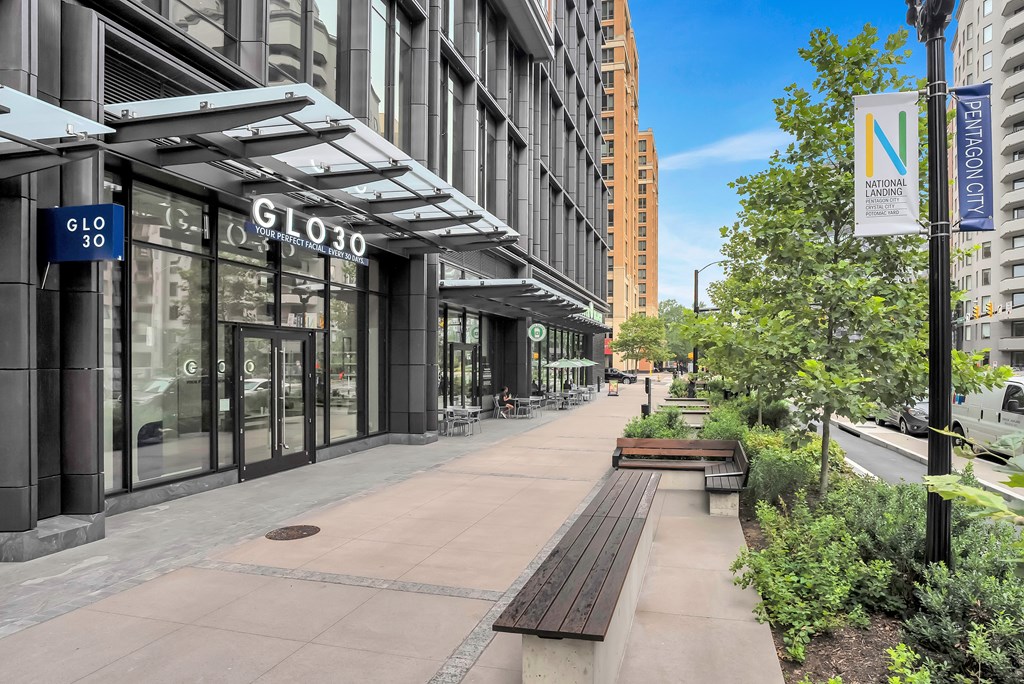 an empty sidewalk in front of a building with glass doors