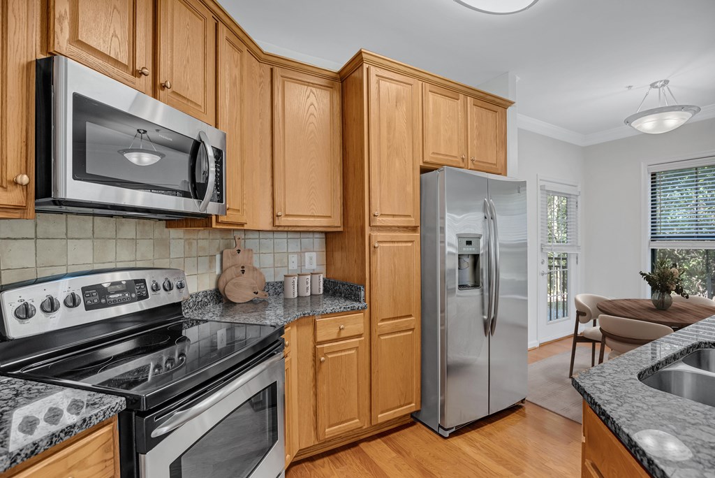 A kitchen with wooden cabinets and a stainless steel refrigerator.