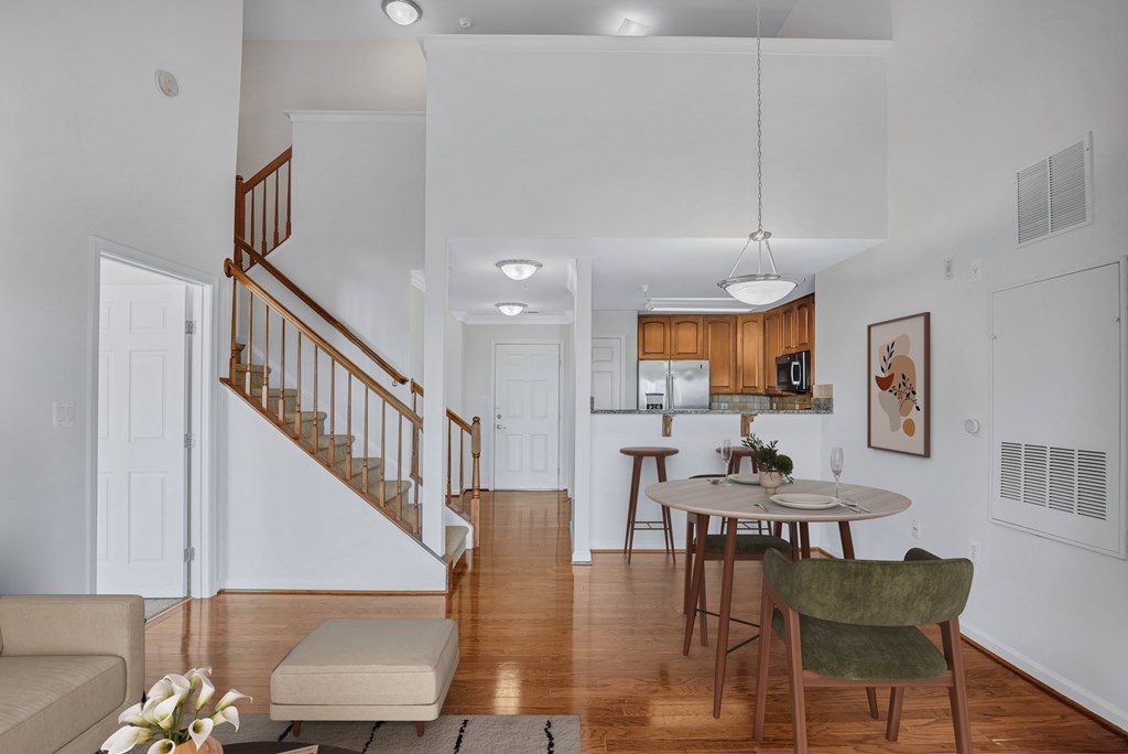 A living room with a staircase and a dining table.