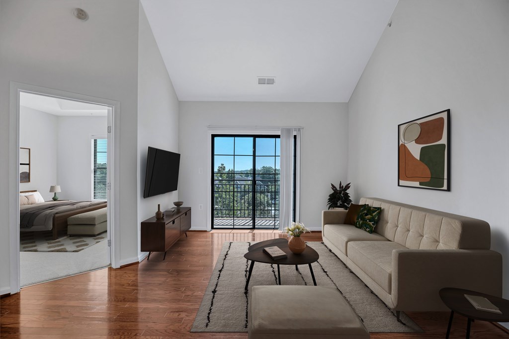 A living room with a couch, a coffee table, and a balcony with a view of the city.