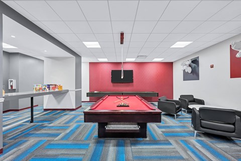 a game room with a red pool table and a television