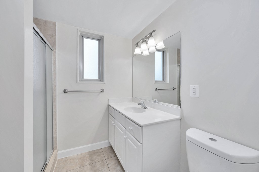 a bathroom with a white sink and toilet next to a shower with a glass door