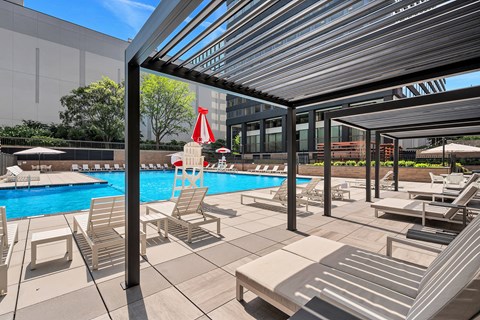 A pool area with sun loungers and a red umbrella.