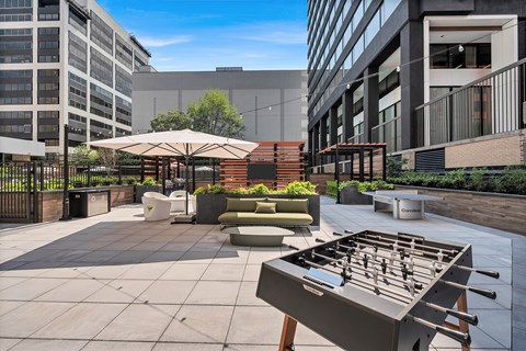 A foosball table is in the middle of a courtyard with a building in the background.